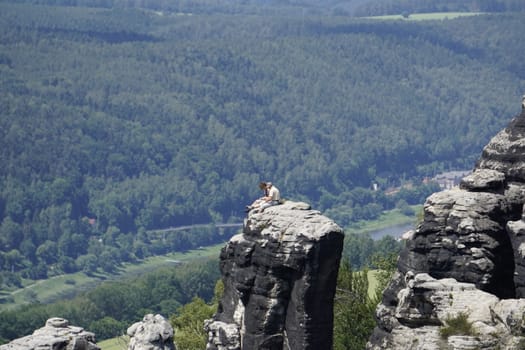 Man and womand sitting on a sandstone rock in the Schrammstein region of Saxon Switzerland, Germany