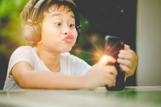 The boy listening to music from smartphone,Boy kissing gesture to  smartphone,The Boy kissing to belove parrent via smartphone