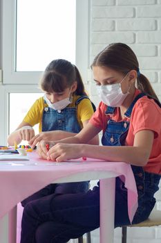 Two sisters in medical masks play board games