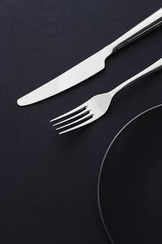 Empty plates and silverware on black background, premium tableware for holiday dinner, minimalistic design and diet concept