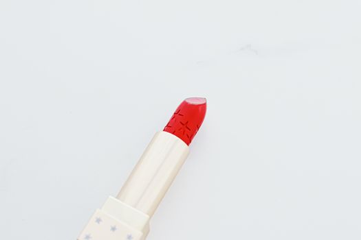 Luxury lipstick in a golden tube on white marble background, make-up and cosmetics concept