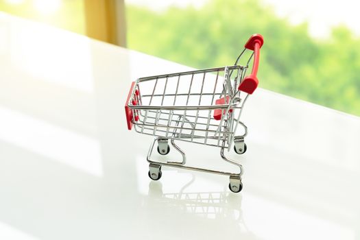 Empty shopping cart trolley on white table with green backgrounds