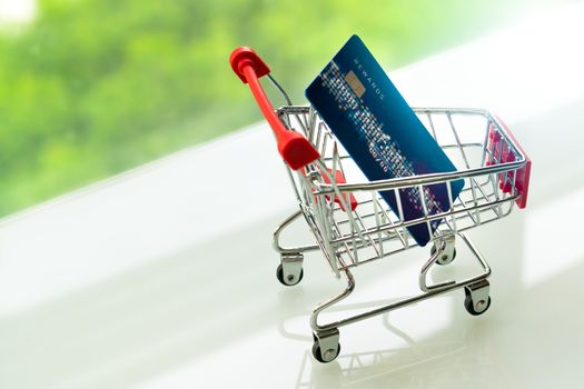 credit card on shopping cart trolley on white table with green backgrounds