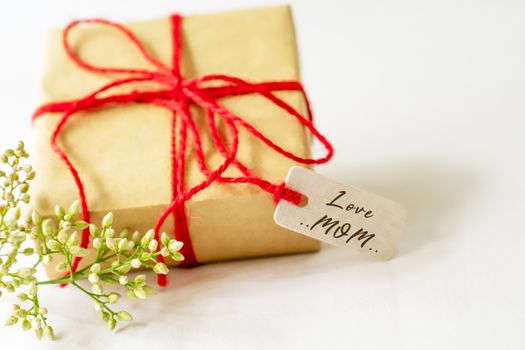 Happy mother's day concept. Gift box and flower, paper tag with LOVE MOM text