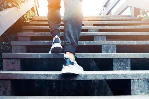 A man step up to success, sport man is climbing on wooden step