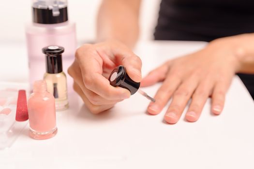 Women applying nail polish on white table with bottles of nail polish and remover, fashion and beauty concept