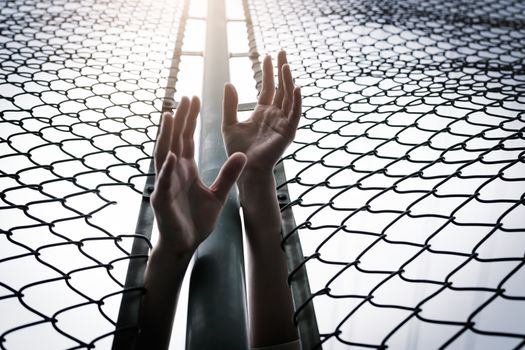 Depressed, trouble, help and chance. Hopeless women raise hand over chain-link fence ask for help