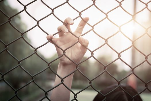 Depressed, trouble, help and chance. Hopeless women raise hand on chain-link fence ask for help