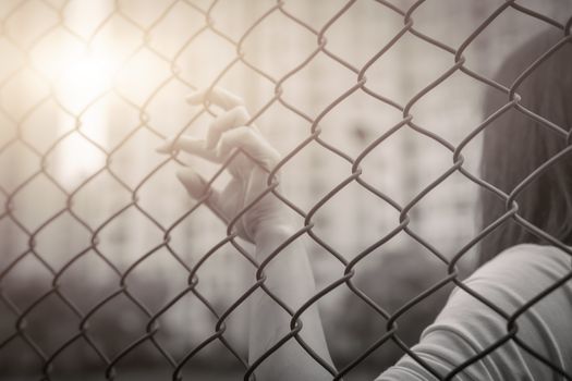 Depressed, trouble, help and chance. Hopeless women raise hand on chain-link fence ask for help