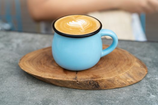 Coffee cup in blue glass on wooden plate