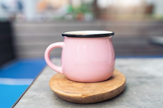 Coffee cup in pink glass on wooden plate