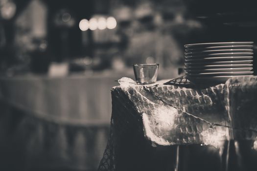 Blurred background of a batch of white dishes on the table with star lighting with black and white filter