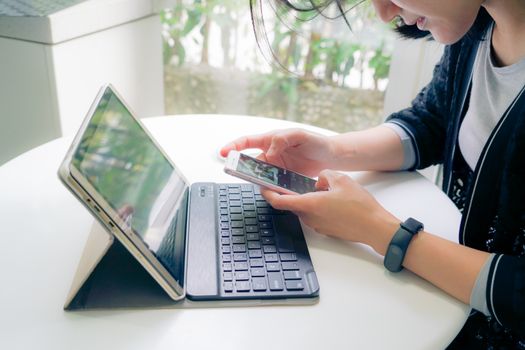 Young student women wearing smart band focus on her tablet computer and smart phone