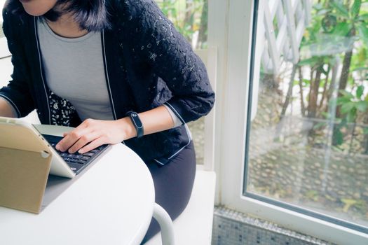 Young student women wearing smart band focus on her tablet computer and smart phone