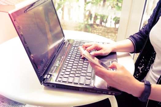 Young student women wearing smart band focus on her laptop computer and smart phone