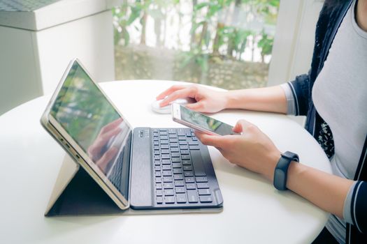 Young student women wearing smart band focus on her tablet computer and smart phone