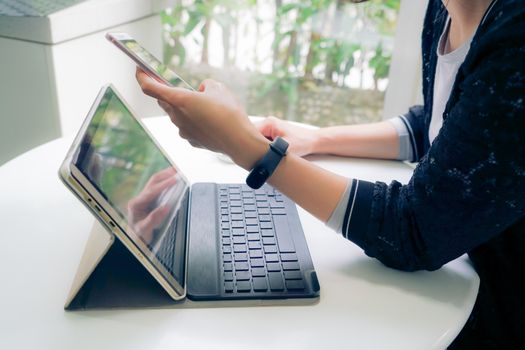 Young student women wearing smart band focus on her tablet computer and smart phone