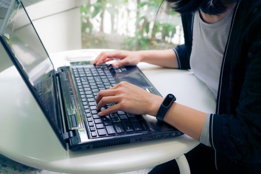 Young student women wearing smart band focus on her laptop computer and smart phone