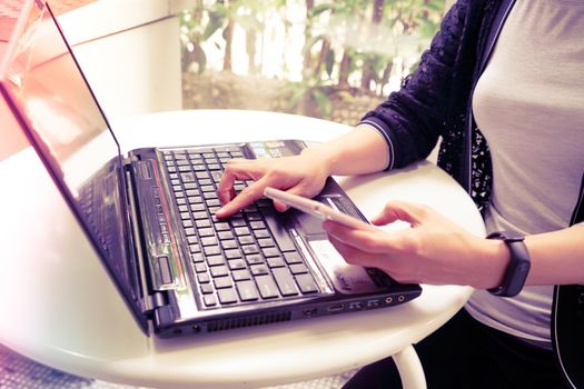 Young student women wearing smart band focus on her laptop computer and smart phone