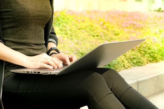 A student woman is typing on laptop computer