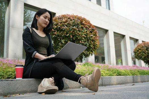 A student woman is typing on laptop computer