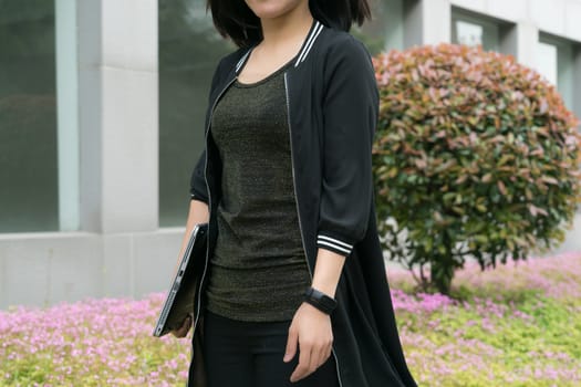 A woman is holding laptop computer while walking