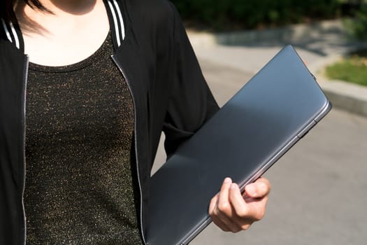 A student woman is holding laptop computer