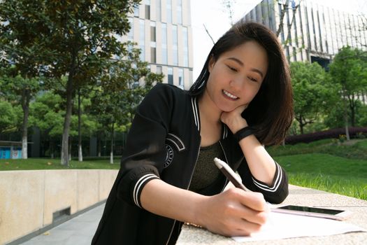 Young student is writing note on white paper