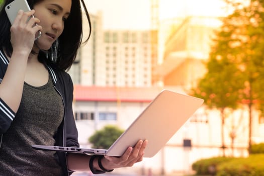 A woman is on call and holding laptop computer