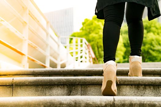 A business women is stepping on stair for successful