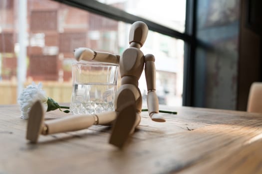 a wood man is sitting and put the arm on the glass of water