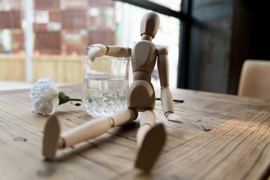 a wood man is sitting and put the arm on the glass of water