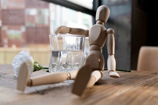 a wood man is sitting and put the arm on the glass of water