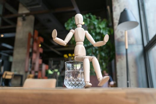 wood man is sitting on a glass of water