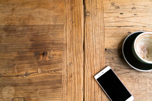 the empty coffee cup with the smart phone on the wooden table