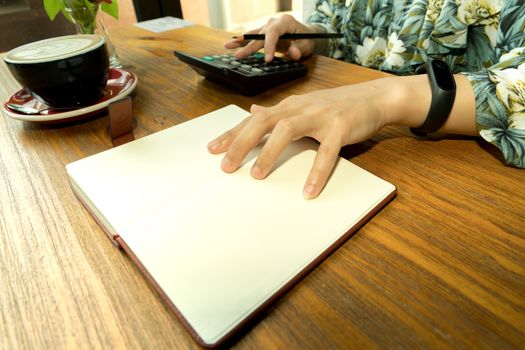 business women is calculating the expense on the wooden table with hot mocha coffee