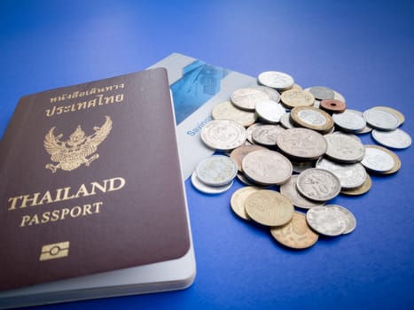 Thailand passport with international coin and saving bank book on the blue background
