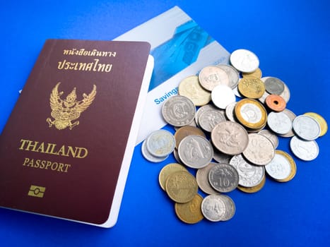 Thailand passport with international coin and saving bank book on the blue background