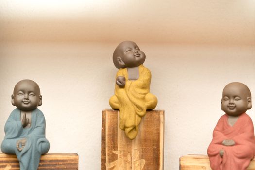 statue of little monk with colorful dress sitting on the wooden box