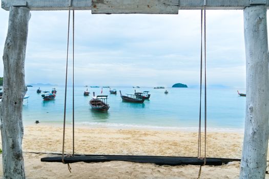 summer holiday, vacation time, the wooden swing on the beach in front of the blue sea