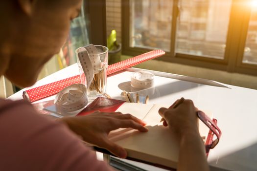 the ruler tape and pencils on the working table of woman drawing the work on the book