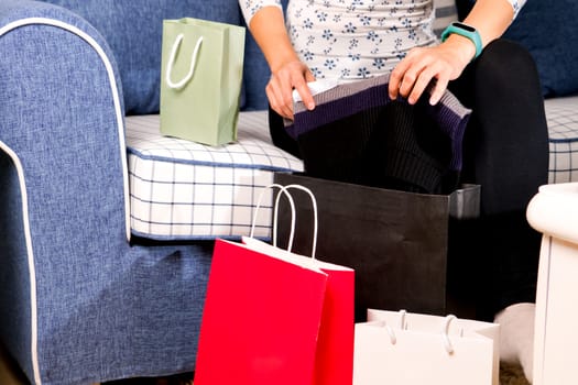 woman sitting on the sofa with the shopping bag is checking purchasing