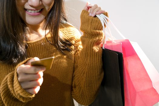 Happy girl holding the colorful shopping bag and credit card for family new year gift