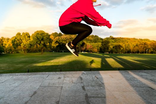 happy young woman is jumping over the garden with overexposure and contrast