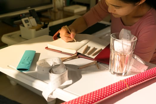 young woman drawing the work on book with the ruler tape and pencils on the working table