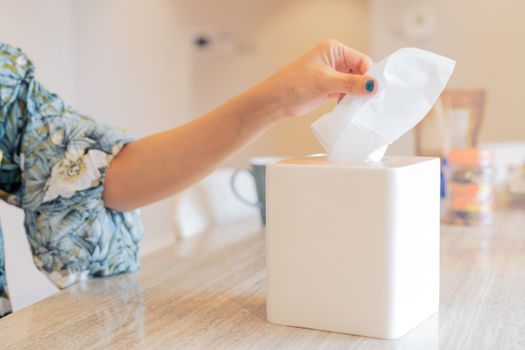 women hand picking napkin/tissue paper from the tissue box