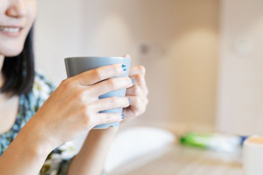 hands holding hot cup of coffee or tea in morning sunlight