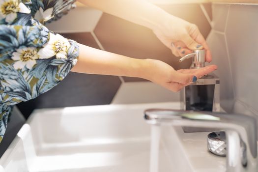 women washing hand with liquid soap in restroom