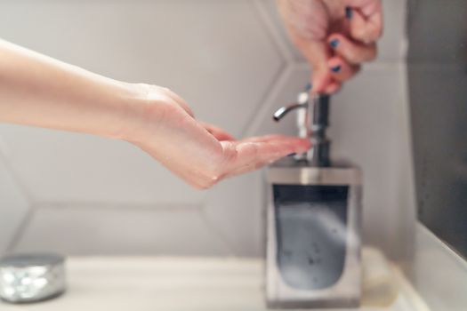 women washing hand with liquid soap in restroom