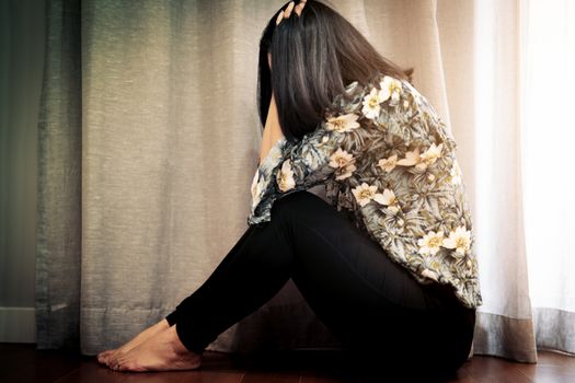 depressed women sitting near curtain in living room, alone, sadness, emotional concept